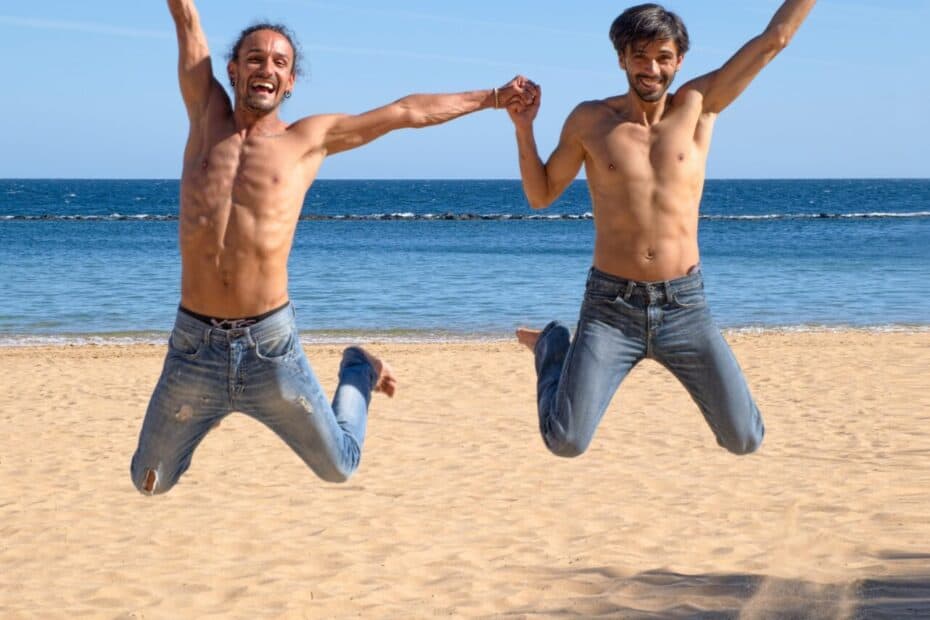 Coverbild zum Artikel über den Mygaysugardaddy Promo Code mit zwei Männern die am Strand mit freuen Oberkörper in die Höhe springen.