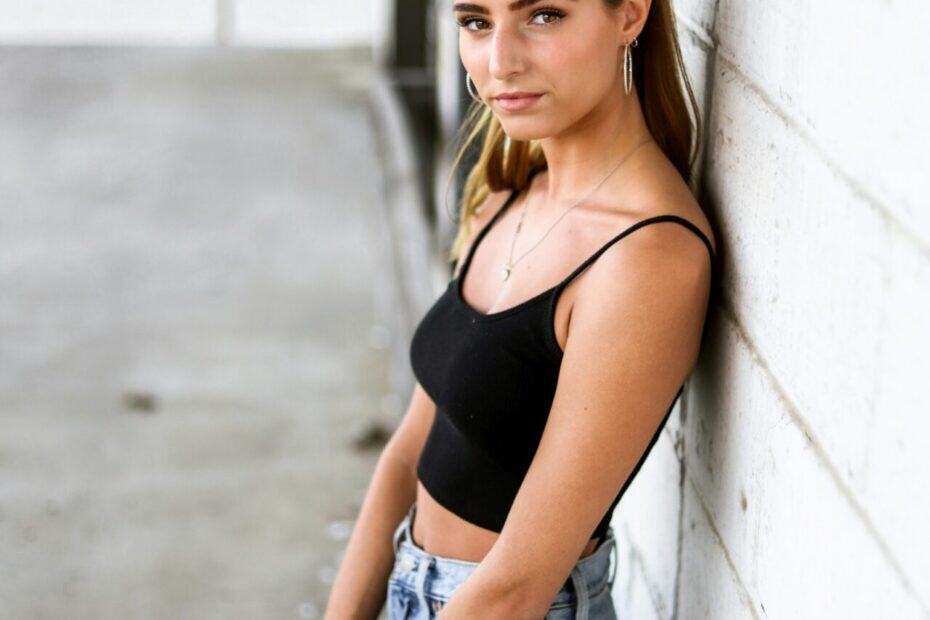 Sexy Sugarbaby mit schwarzen Top und Jeans an Wand lehnend. Treffe sie mit Mysugardaddy Rabatt Code